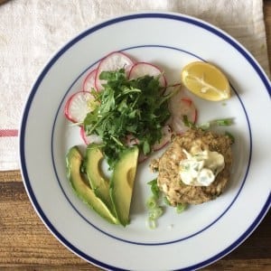 white and blue plate with avocado, radishes, greens, and lemon