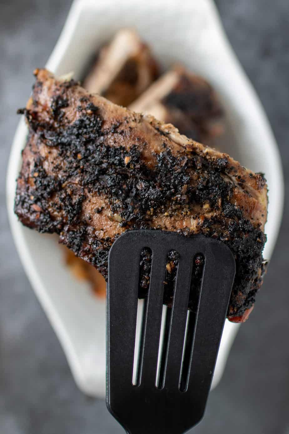 coffee rubbed ribs stacked on each other and a spatula holding them up