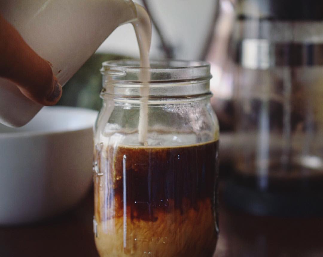 dairy free cream being poured into a jar of coffee