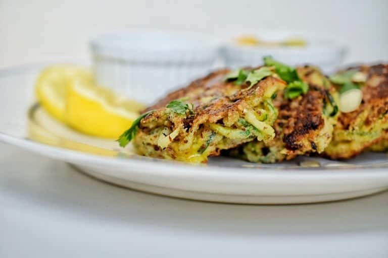 closeup of zucchini fritters with lemon in the background