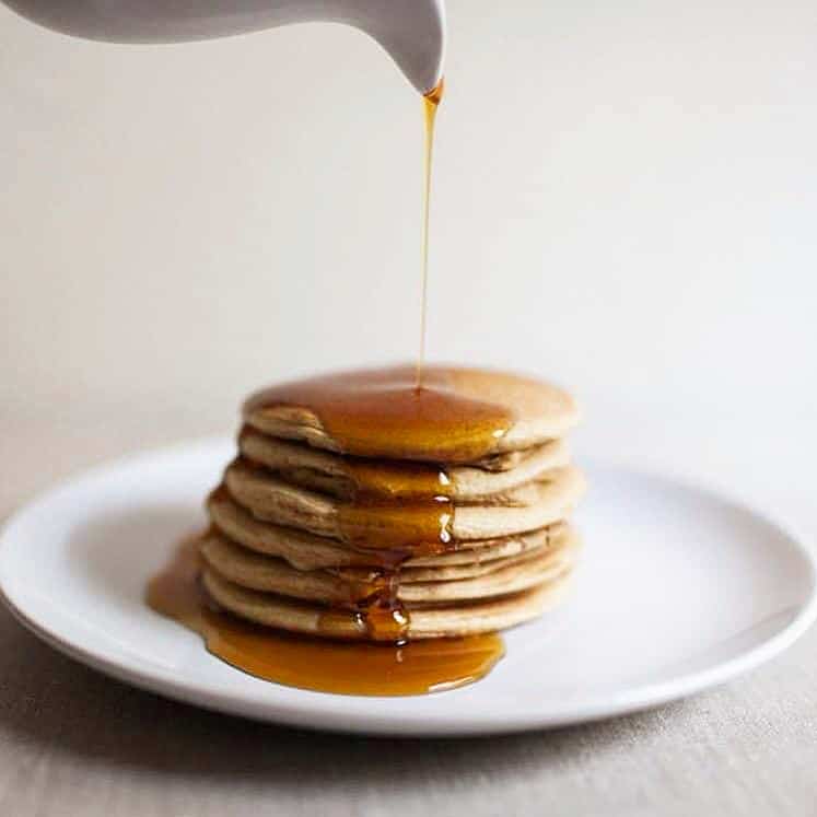 A stack of plantain pancakes drizzled with maple syrup.