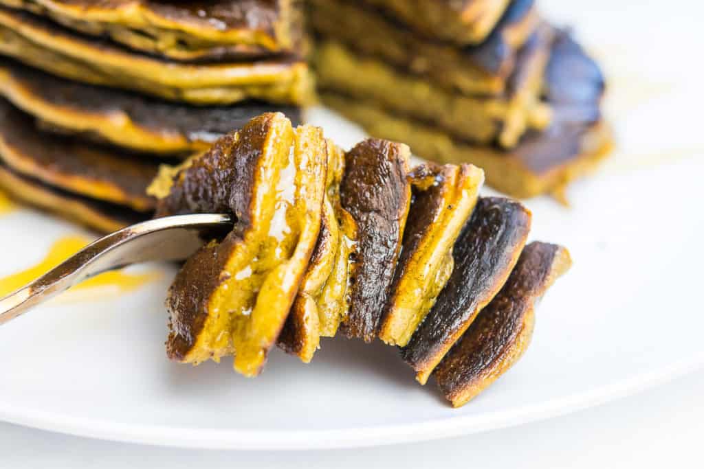 A bite of fluffy plantain pancakes loaded on a fork.