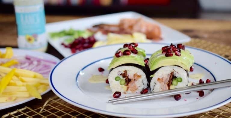 sushi with avocado and pomegranate arils on a white plate
