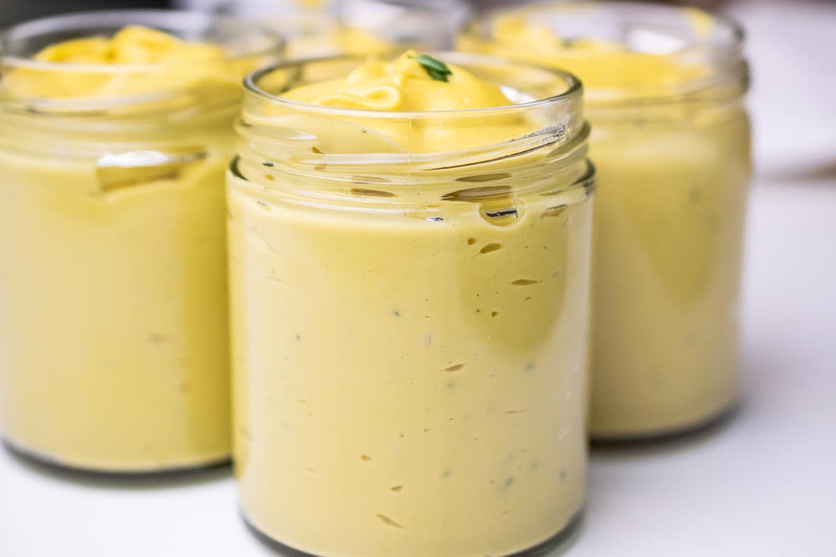 a close up on the side of a jar with yellow creamy vegan custard