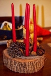 red candles on a wood block with pine cones
