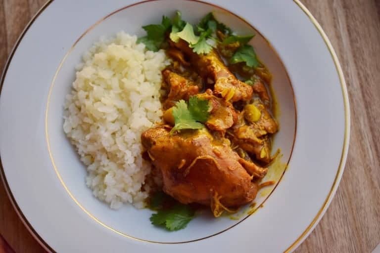 indian butter chicken and rice on a white plate