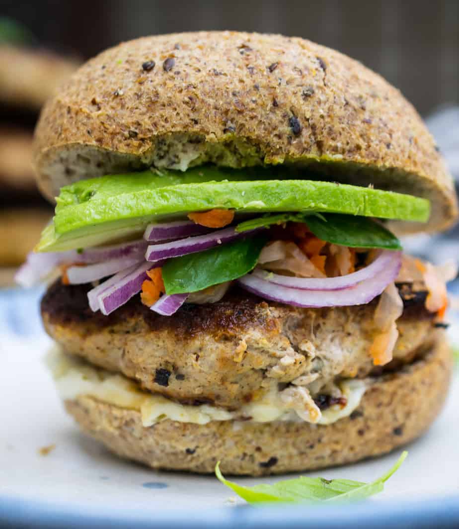 close up of thai turkey burger - with turkey patty, avocado, red onion, and garnish