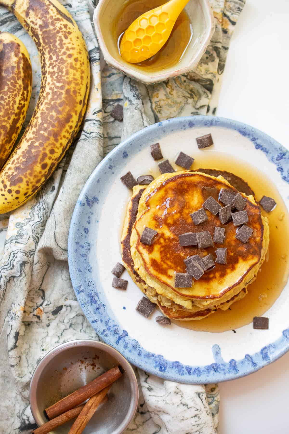 nut free paleo pancakes with chocolate chips served next to bananas, cinnamon and honey