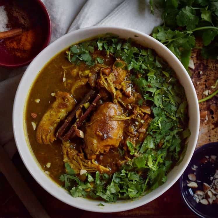 bowl of indian butter chicken surrounded by greens