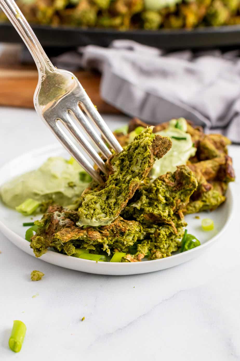 close up of vegetable waffles on plate pinched by fork