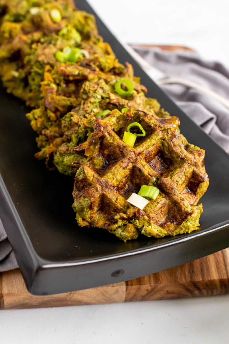 vegetable waffles served on a black dish garnished with green onion 