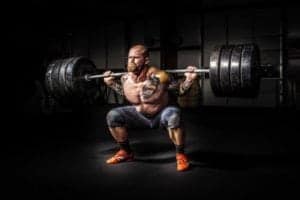 muscular tattooed man lifting heavy weights