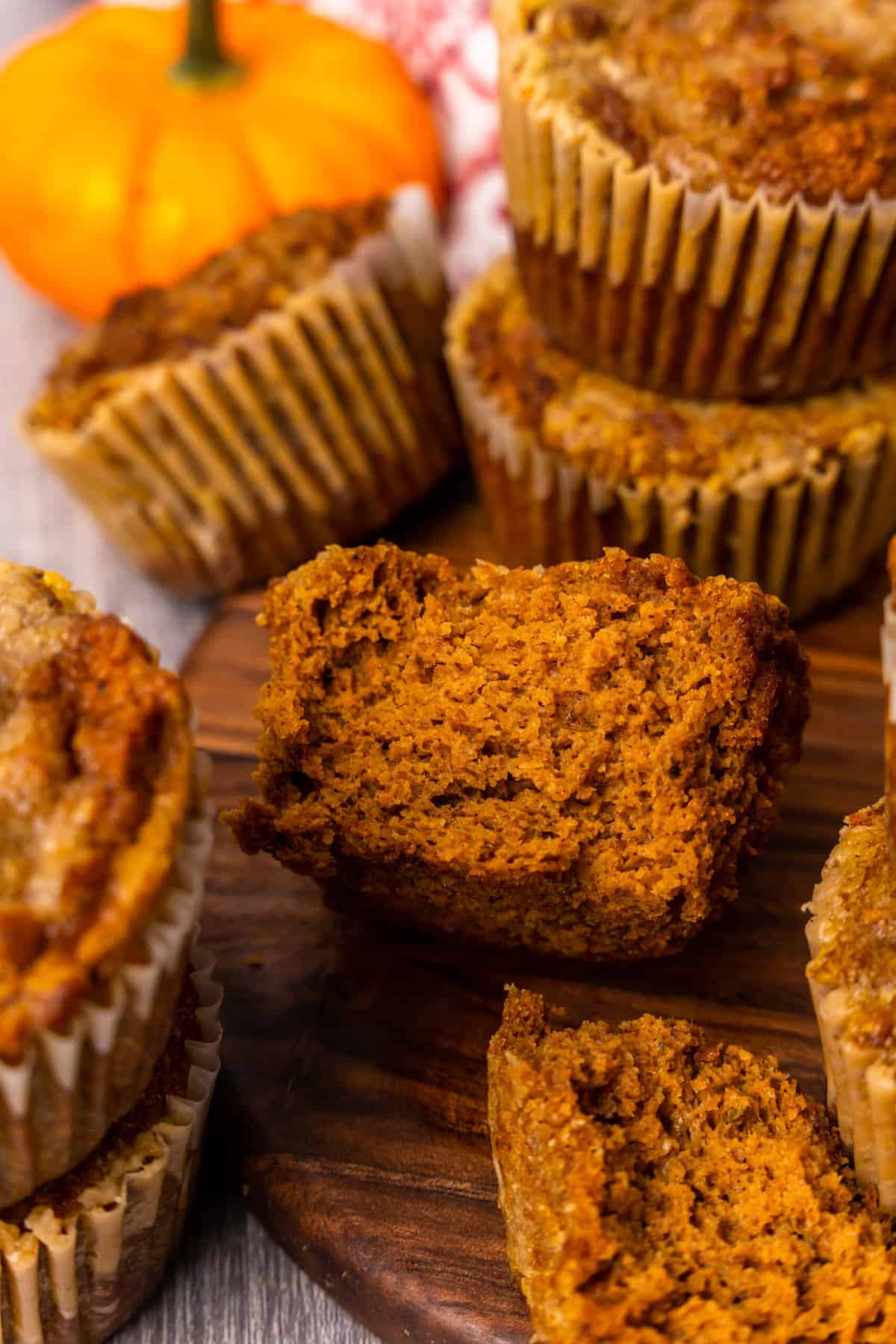 nut free pumpkin spice muffins on a wooden board, stacked and one in front bitten in to