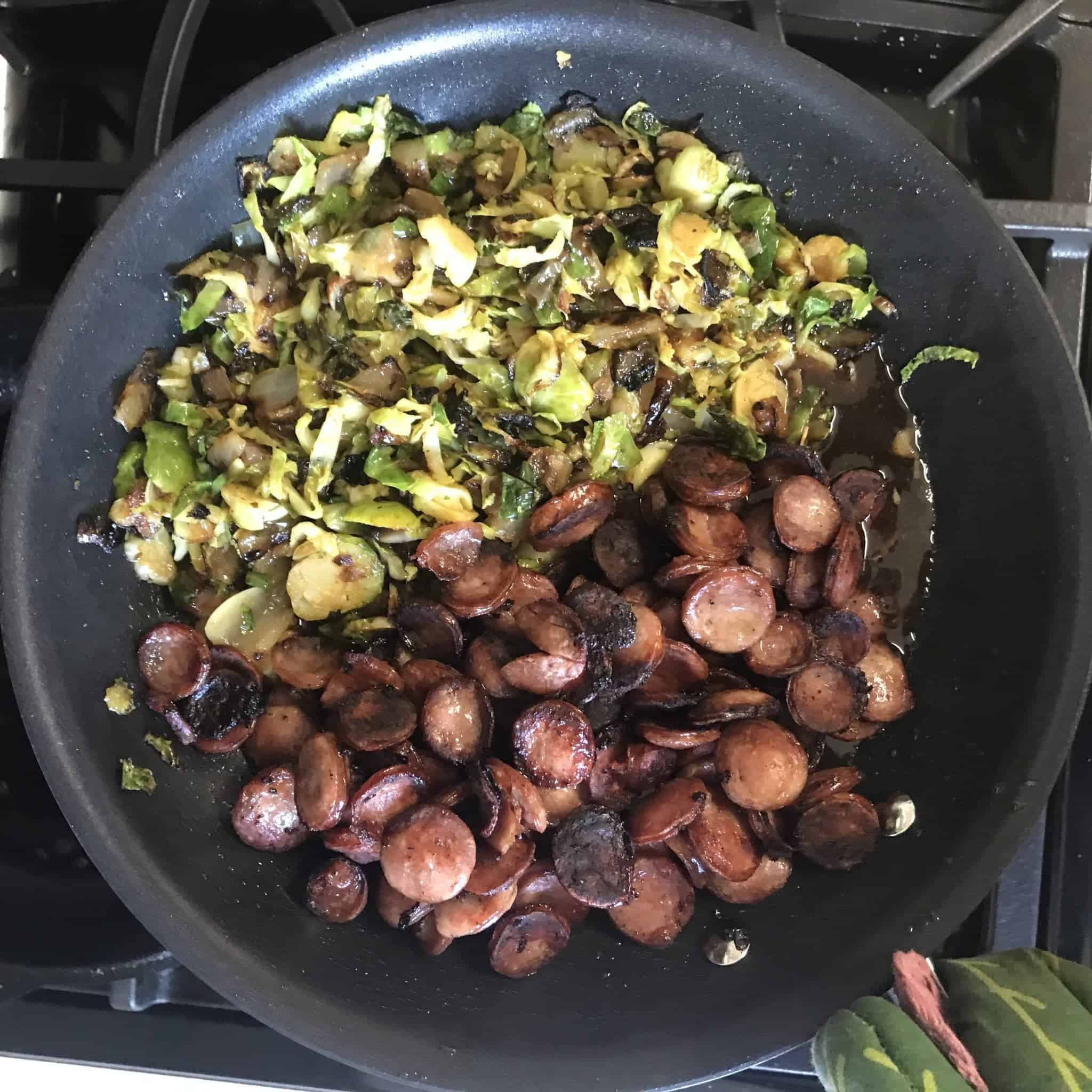 brussel sprouts and sliced bratwuest cooked in a skillet side by side 