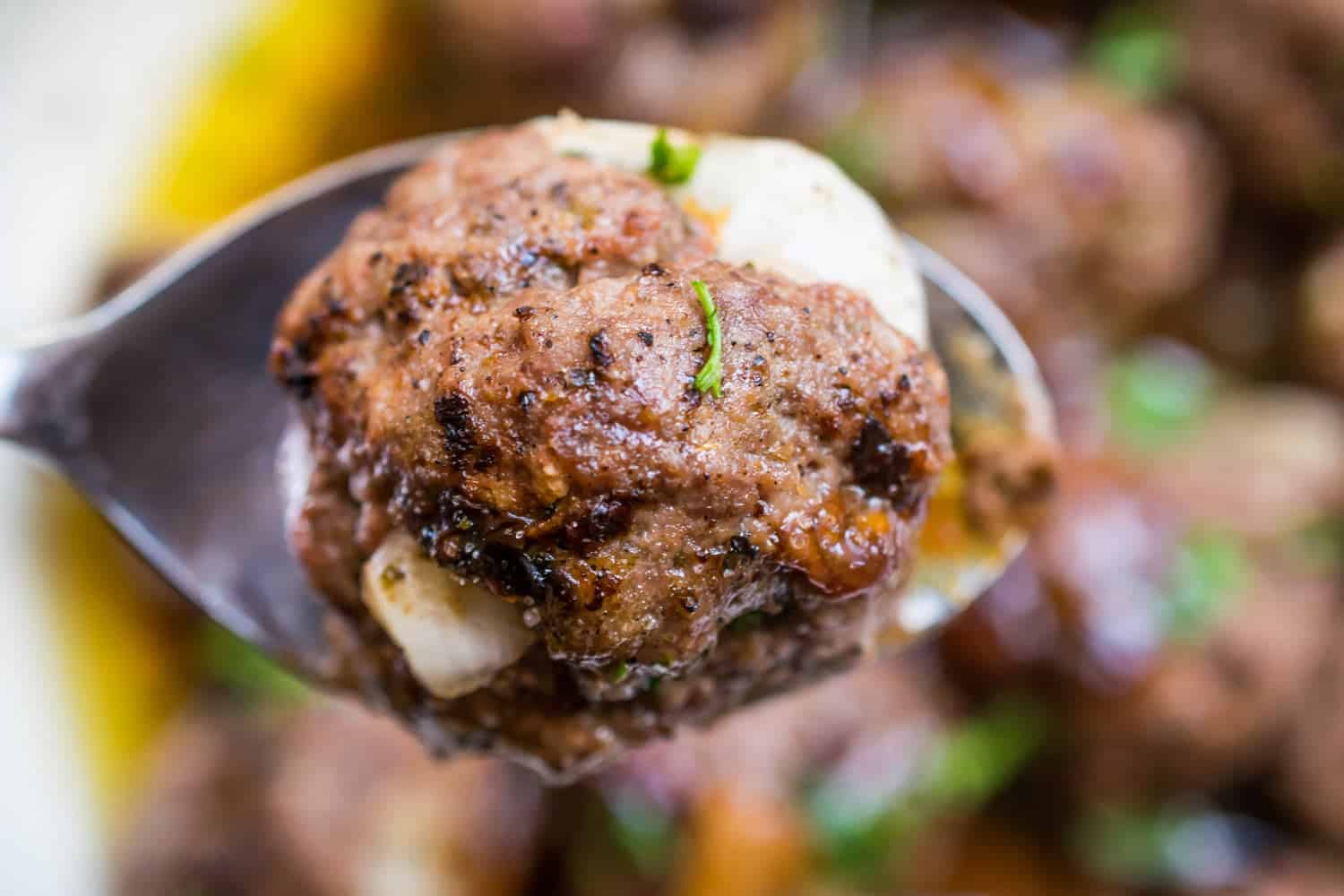 a close up of one carne asada meatball on a spoon