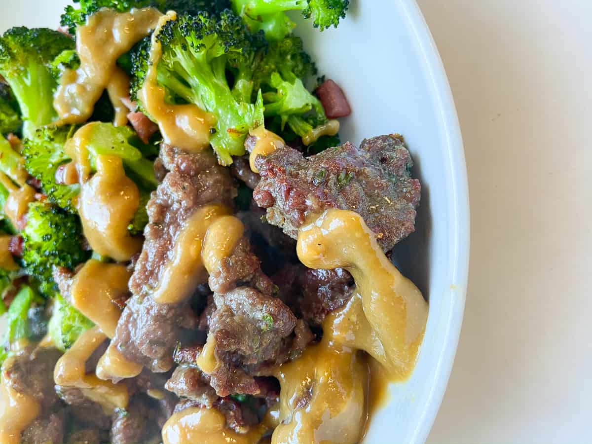 beef and broccoli with tahini sauce in a bowl