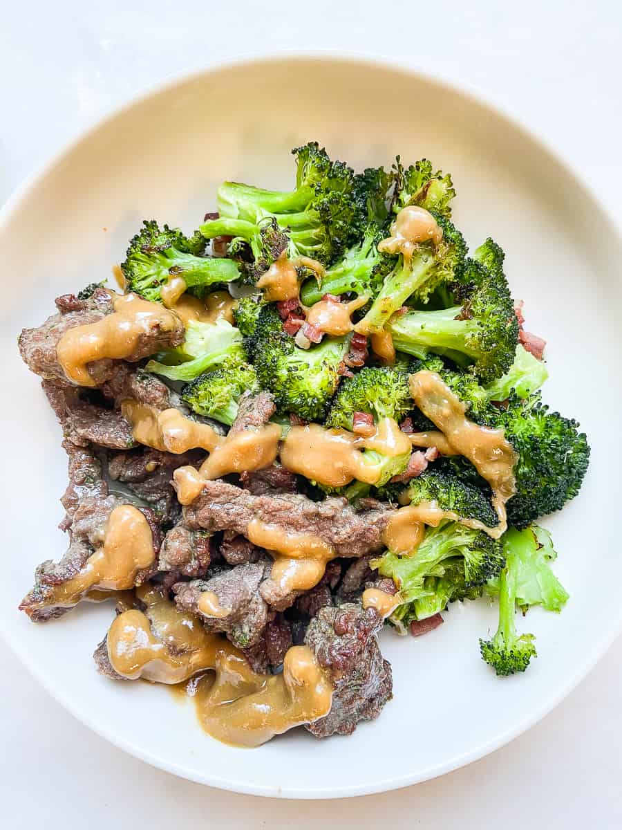beef and broccoli with tahini sauce in a white bowl 