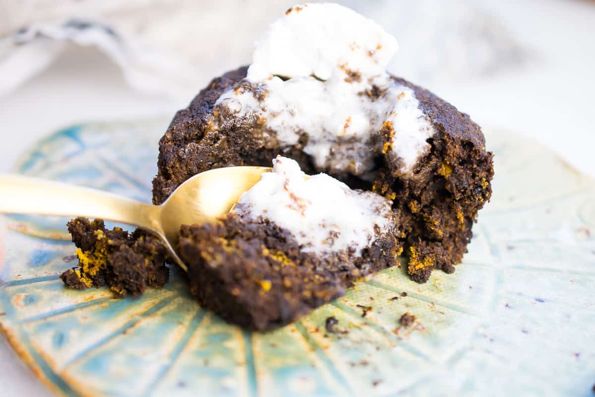 AIP MUG CAKE with a spoon going into it, topped with coconut whipped cream