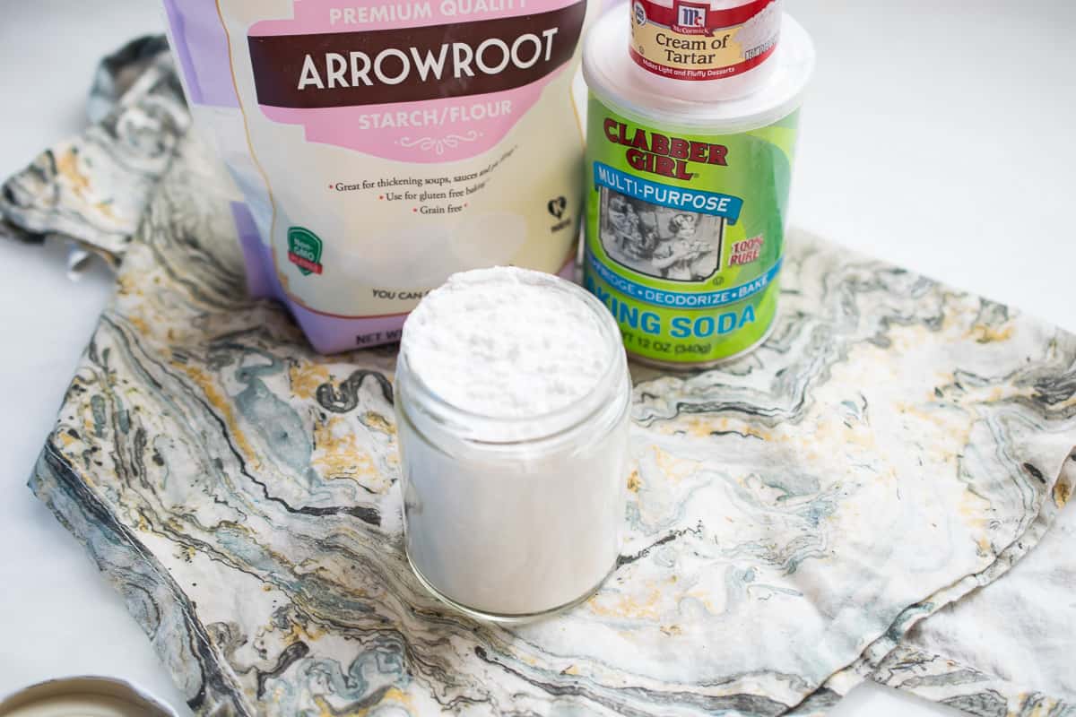 a bag of arrowroot starch/flour, a can of baking soda, a small container of cream of tartar, a glass jar with white powder in it- baking powder