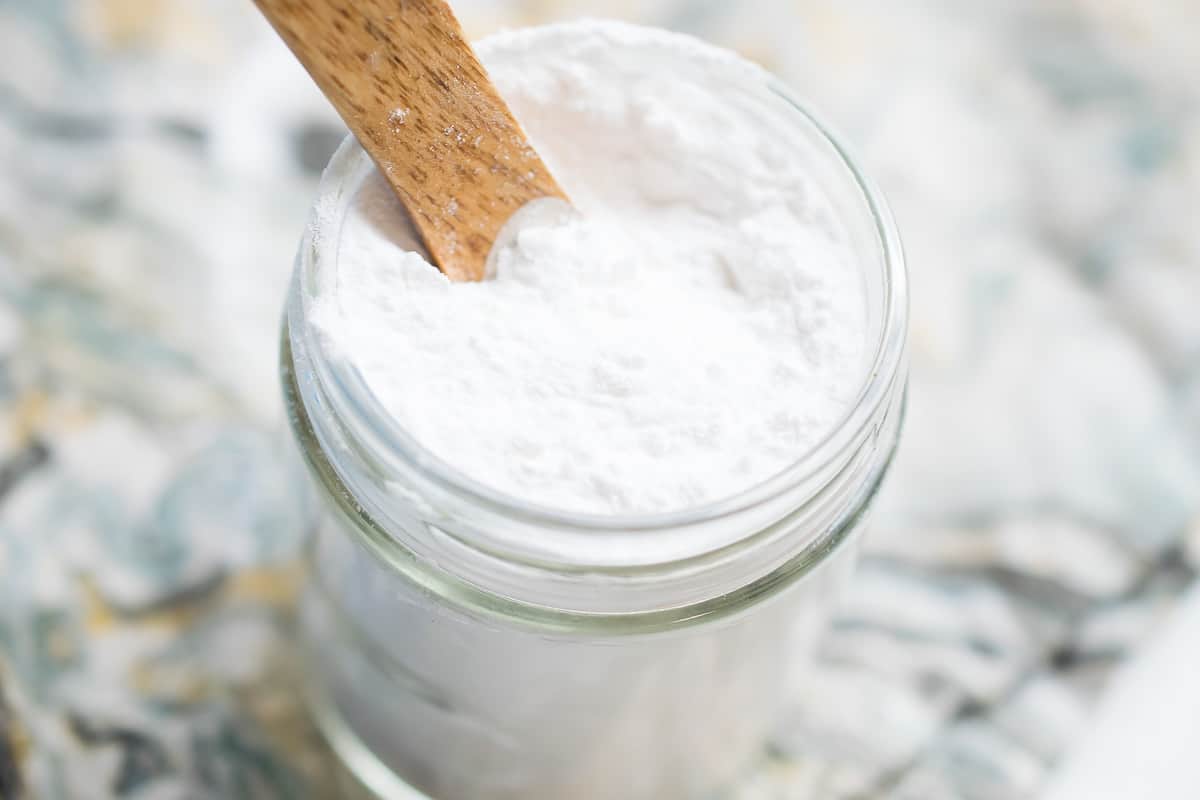 grain free aip baking powder in small glass jar with a wooden spoon dipped into it