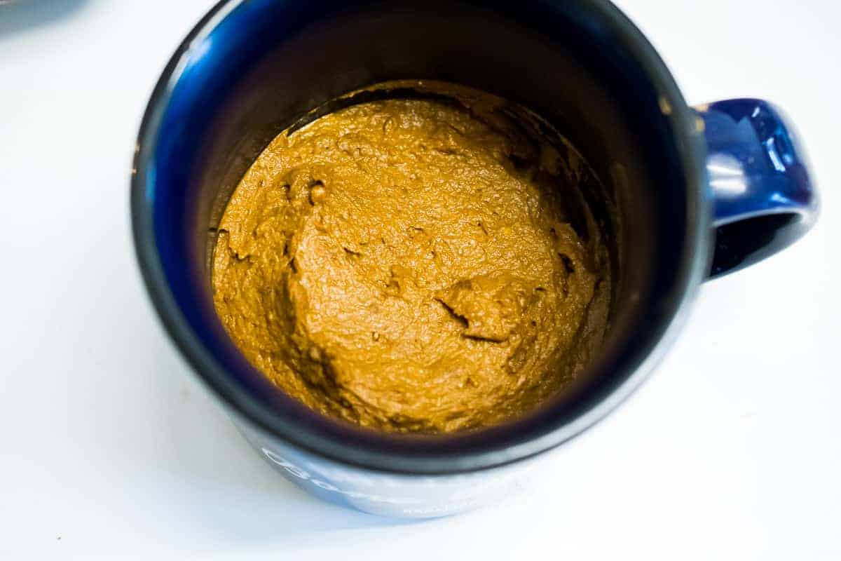 AIP Brownie Mug Cake batter smoothed out into a dark blue coffee mug.