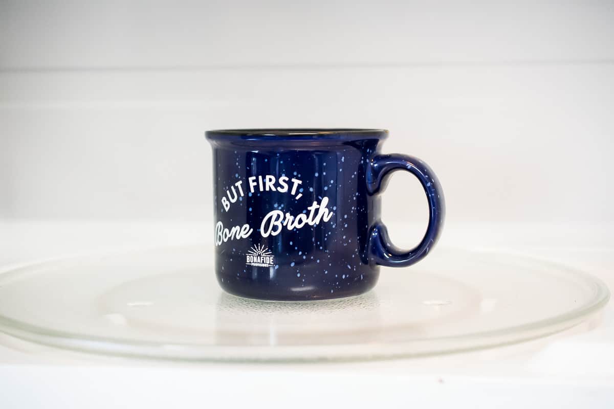 A dark blue coffee mug full of AIP Brownie Mug Cake batter in the microwave.