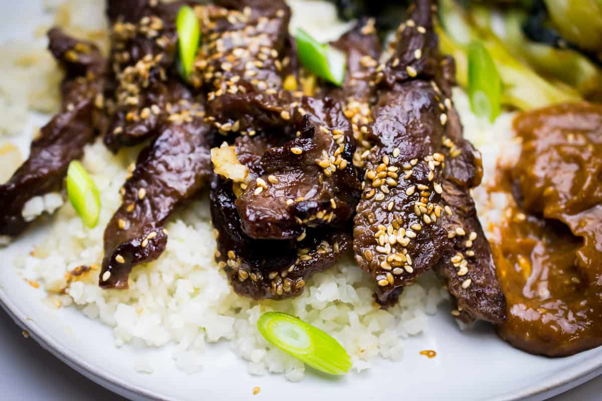 whole korean beef close up on a plate with cauliflower rice and almond sauce 