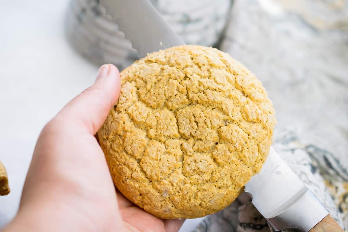 aip english muffin held in hand being sliced in half