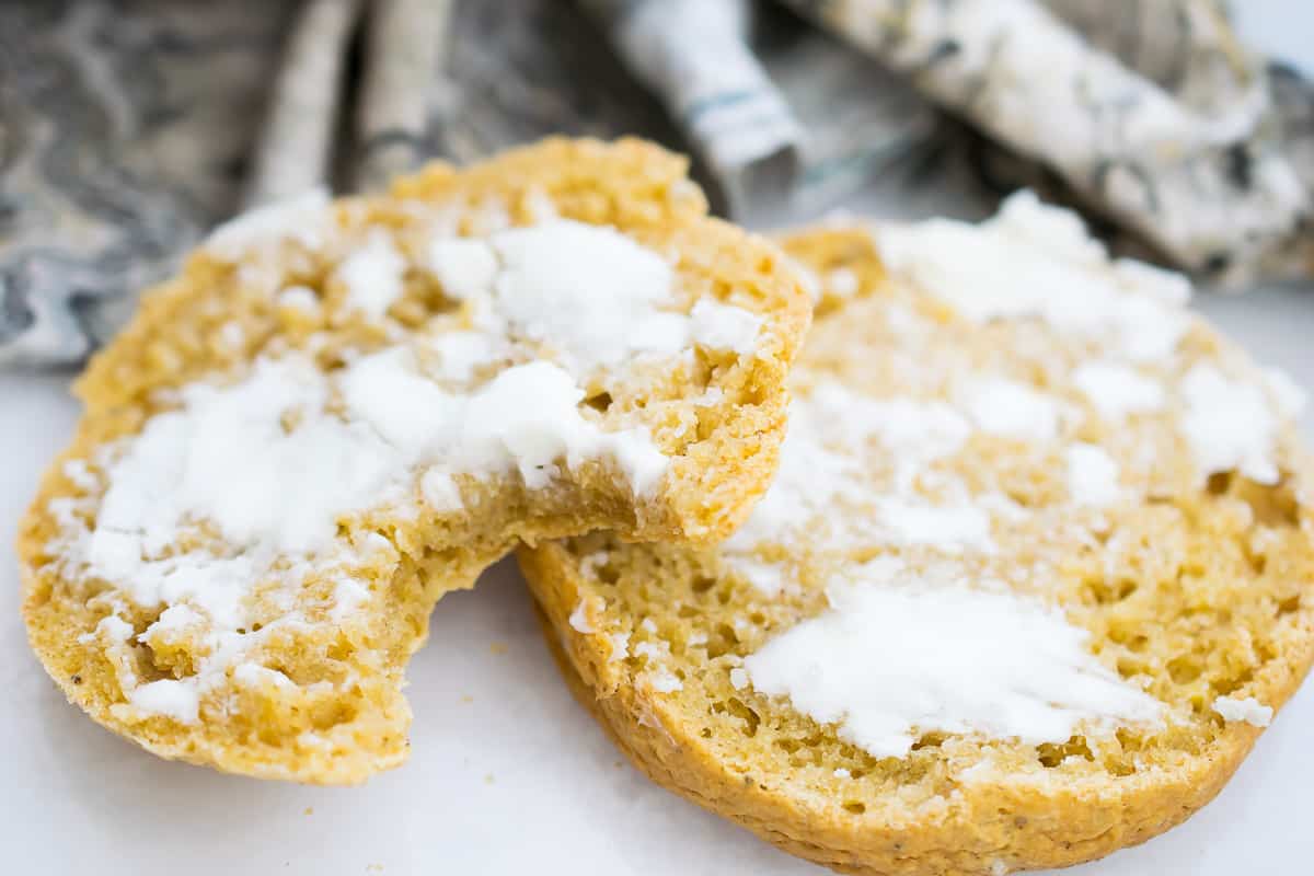 aip english muffin cut in half, one half with a bite taken out of it, both slathered with coconut cream