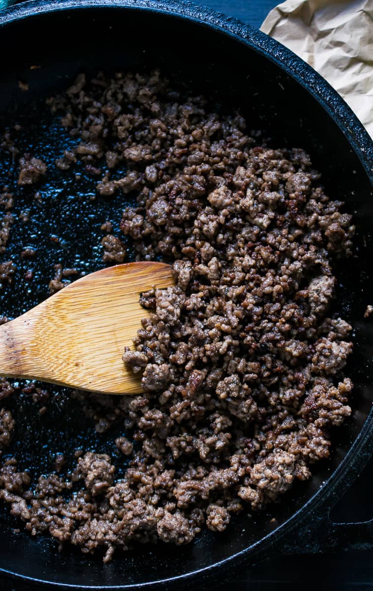 crispy ground beef in a cast iron skillet with wooden spatula 