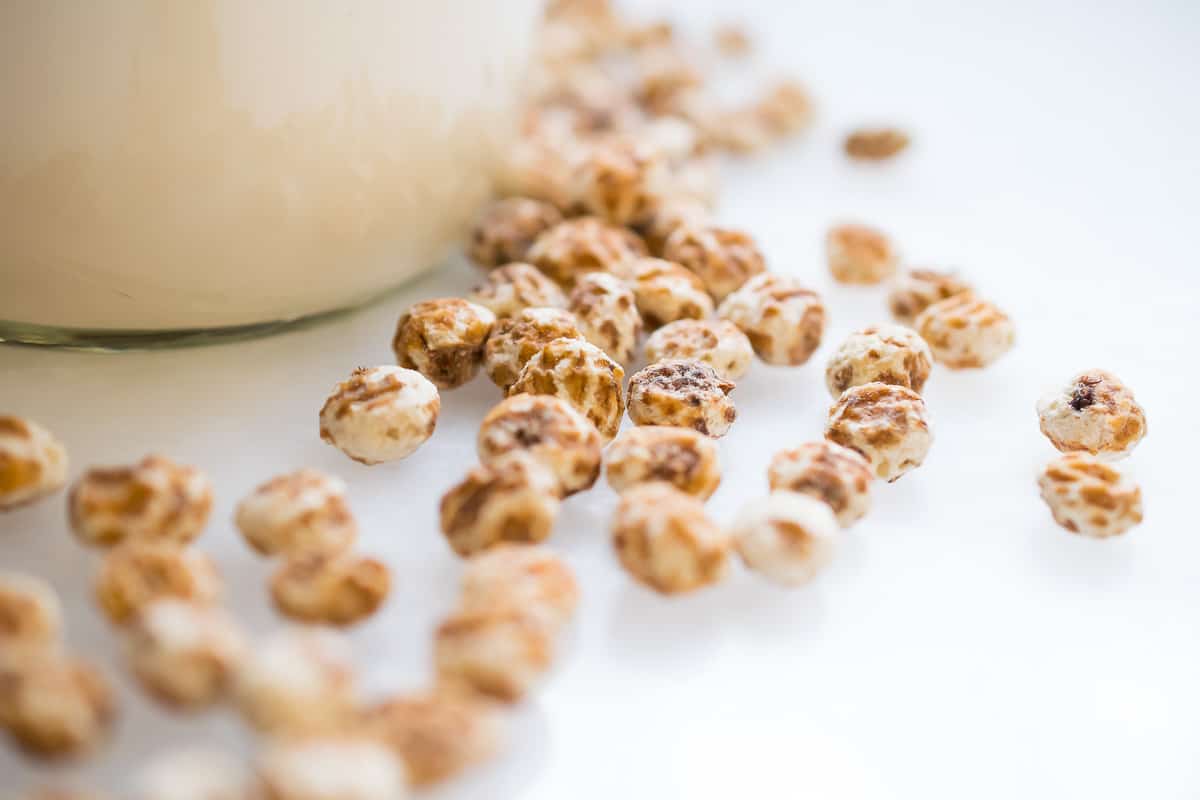 a close up of tiger nuts on the table in the background a jar of tiger nut milk