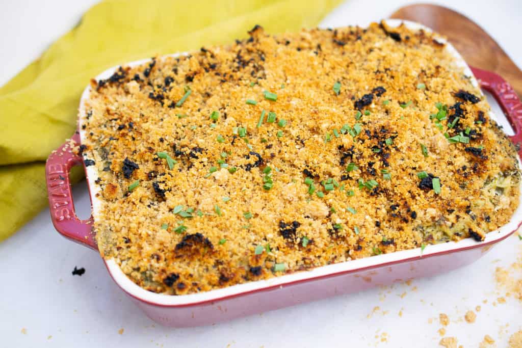 Cheesy dairy-free AIP Chicken Casserole with spinach, baked and bubbly in a red casserole dish, topped with crunchy pork panko.