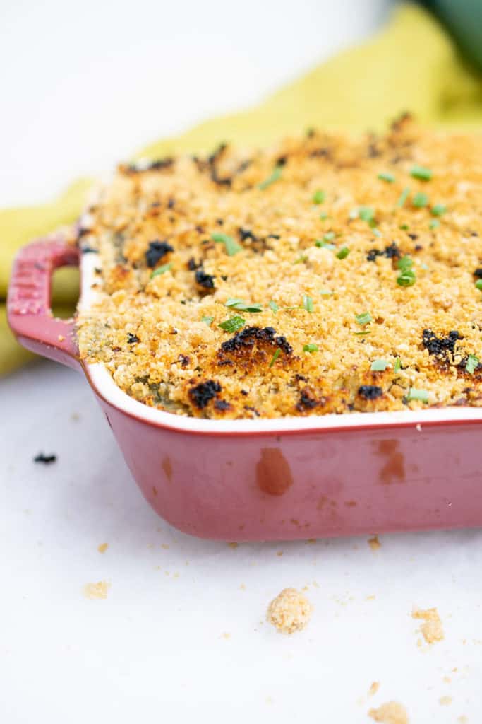 Cheesy dairy-free AIP Chicken Casserole with spinach, baked and bubbly in a red casserole dish, topped with crunchy pork panko.