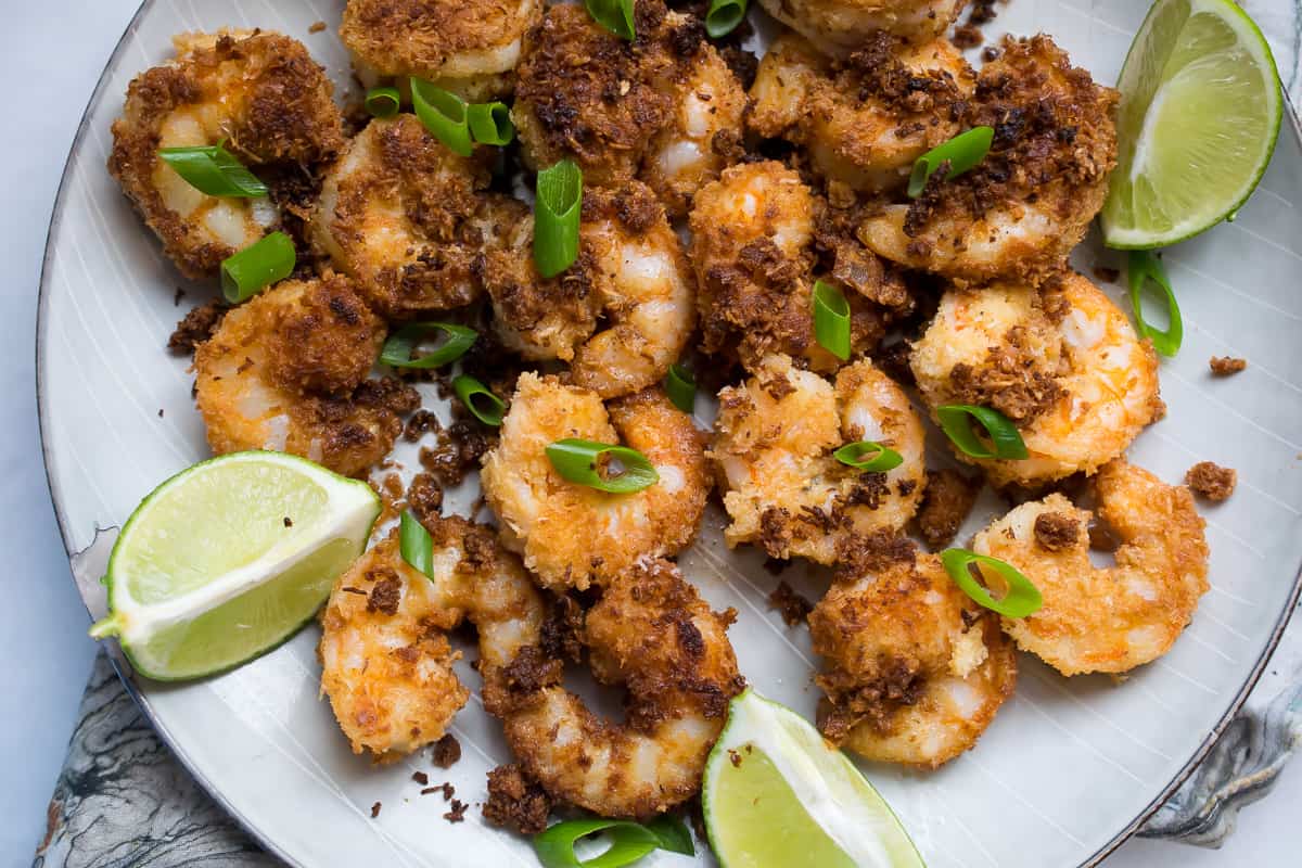 easy coconut shrimp served on a platter, garnished with green onion, wedge of lime on the side