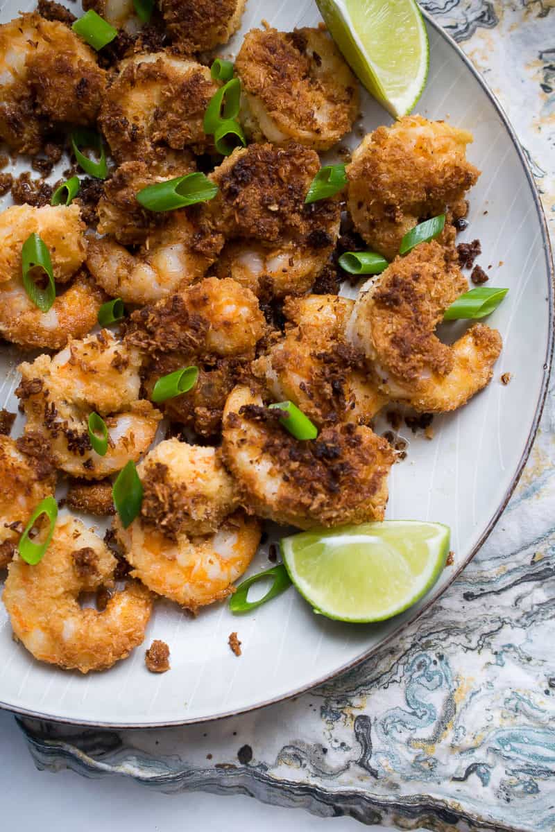 whole30 coconut shrimp on dish garnished with green onion and wedge of lime on side 