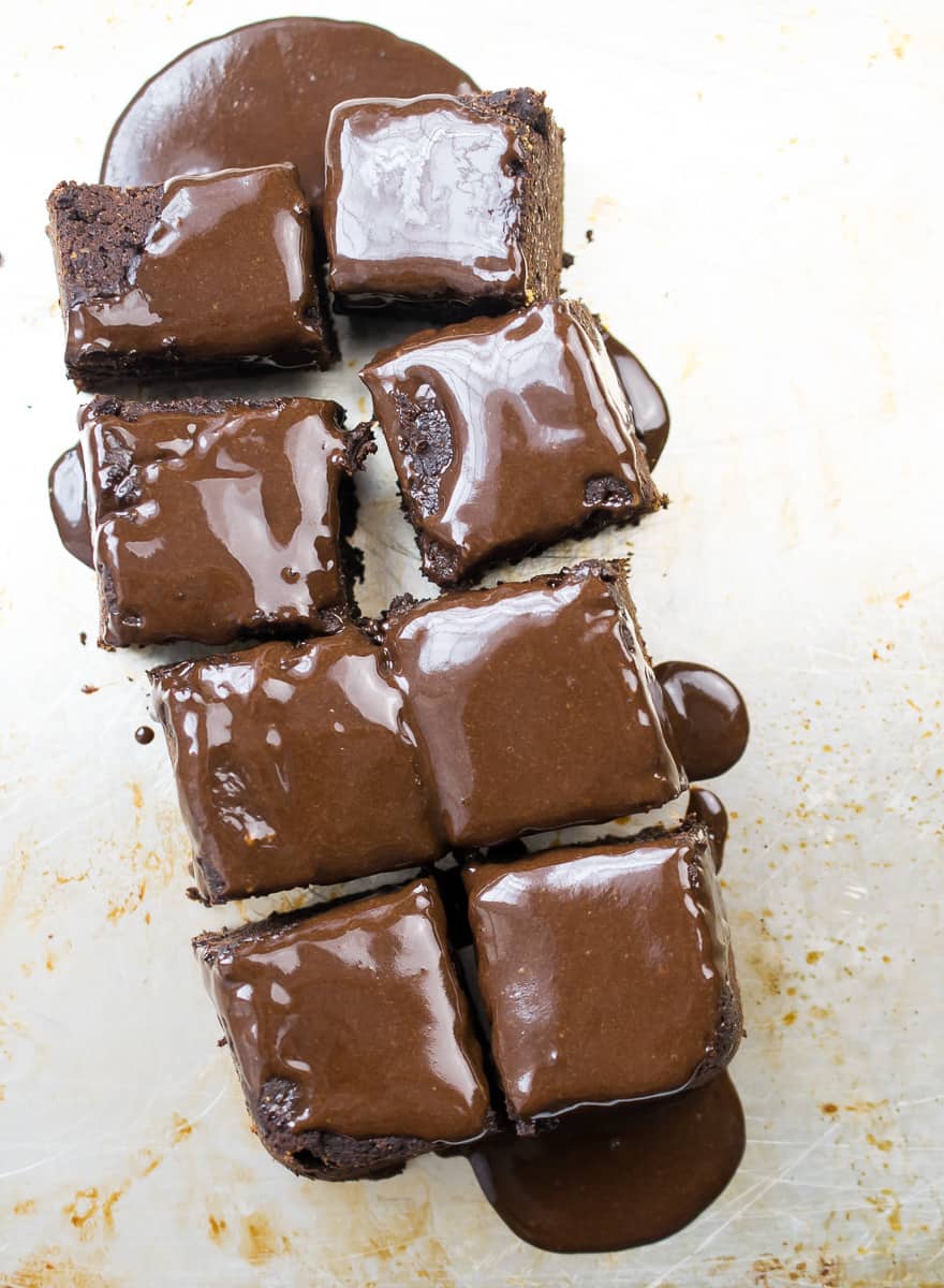 8 aip glazed brownies with a white background and delicious gooey glaze dripping all over them 