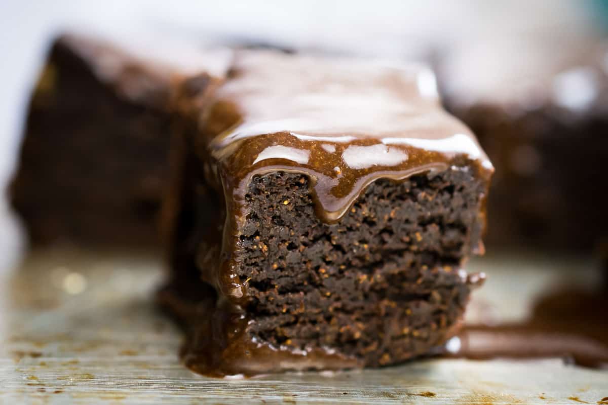 close up of a dense chocolate brownie with chocolate glaze dripping over it