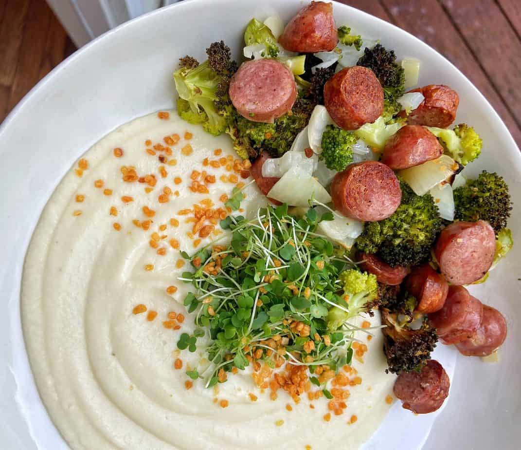 air fryer broccoli and bratwursts with onion and garnished with microgreens and cauliflower puree on the side