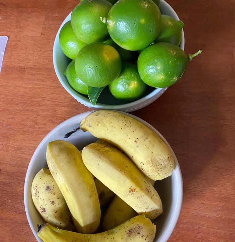 two bowls- one with whole bright green limes and the other with small yellow and brown spotted ripe plantains