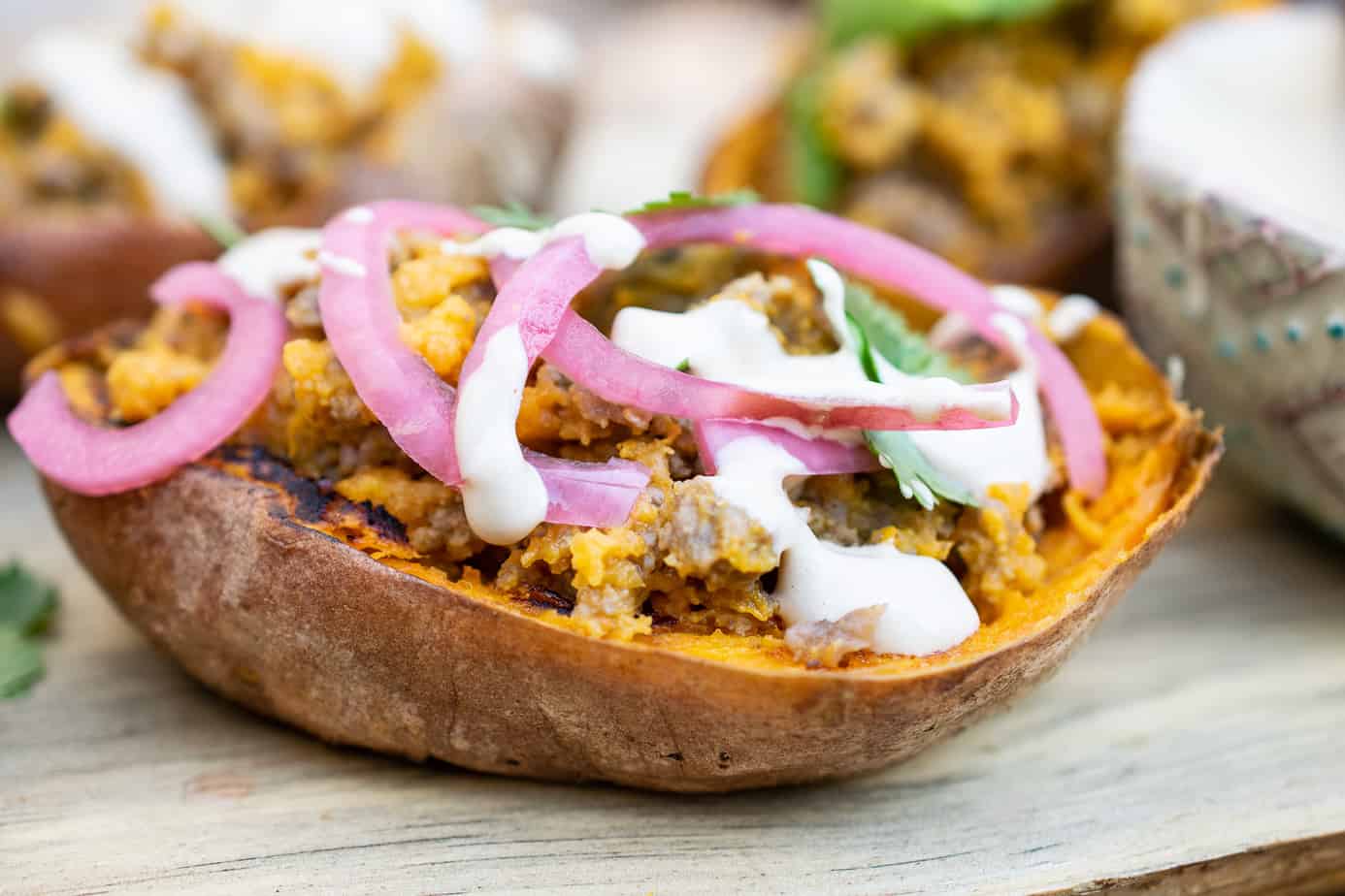 stuffed sweet potato skin- garnished with pickled red onion. drizzed with mayo-mustard sauce 