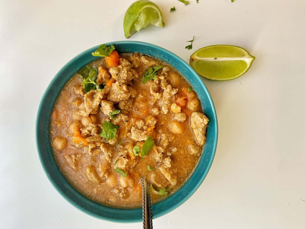 instant pot turkey and garbanzo soup in blue bowl with lime on the side