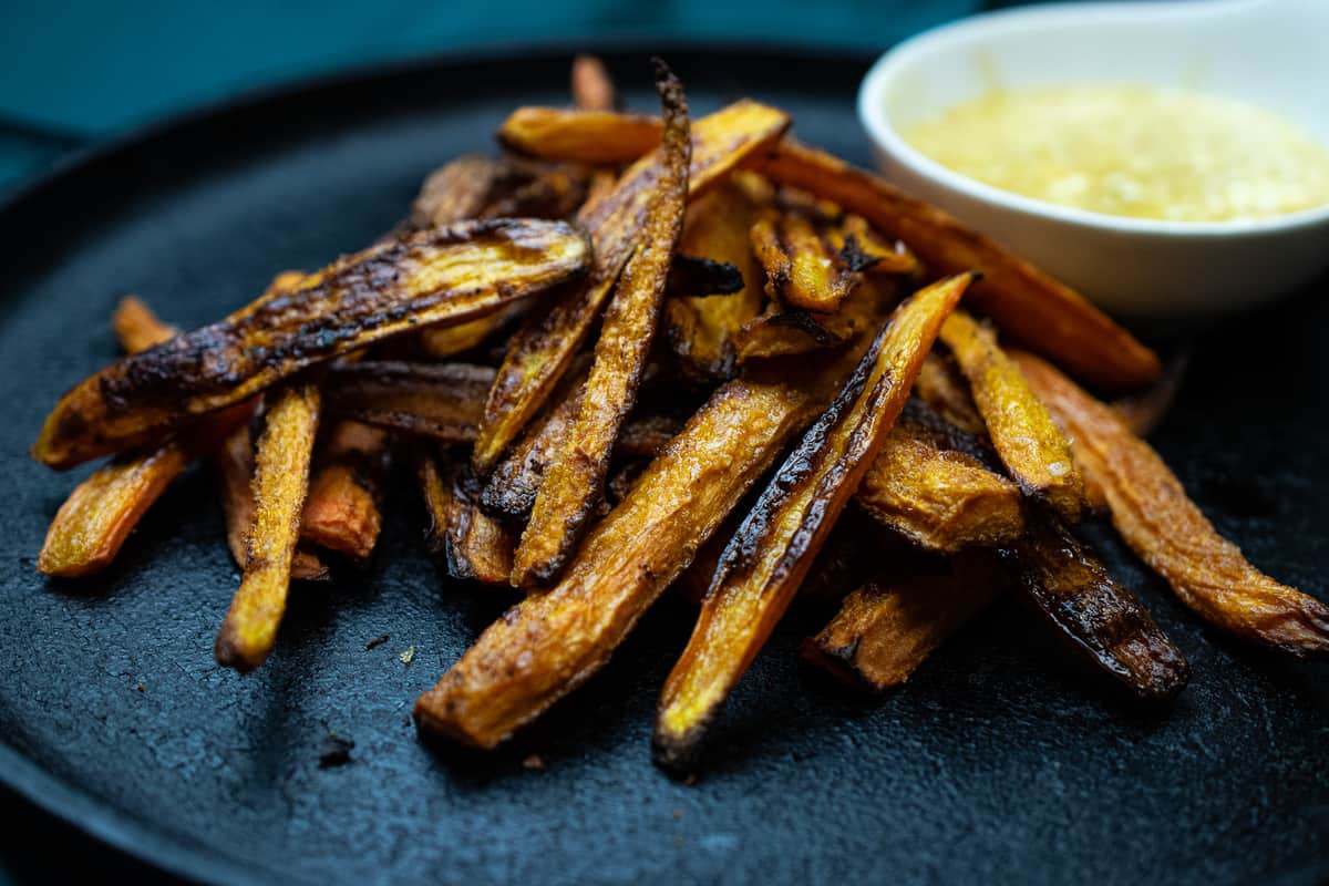 pile of carrot fries on cast iron skillet with sipping sauce