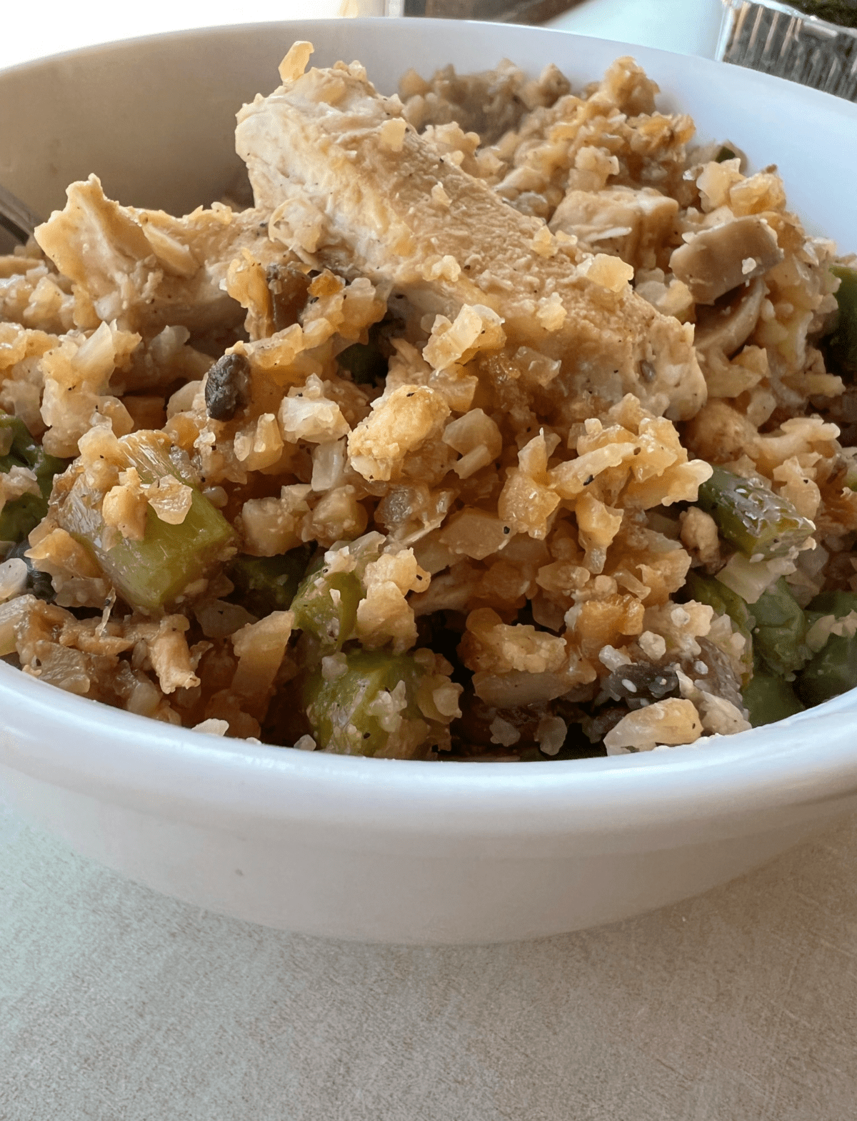 close up on cauliflower rice an chicken in a white bowl