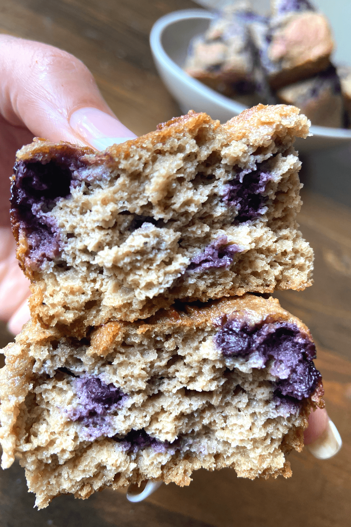 two halves of blueberry brea stacked and being help in a hand, moist and delicious blender batter blueberry bread thats golden brown 