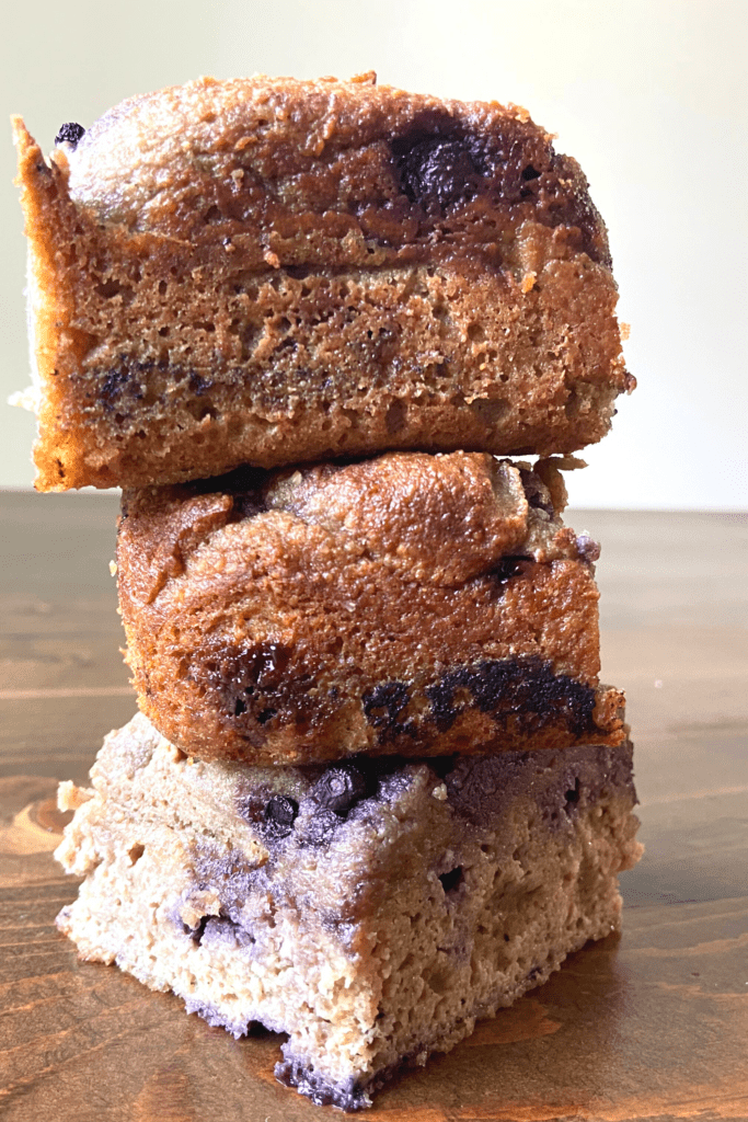 three keto blueberry breads stacked on each other on a wooden table