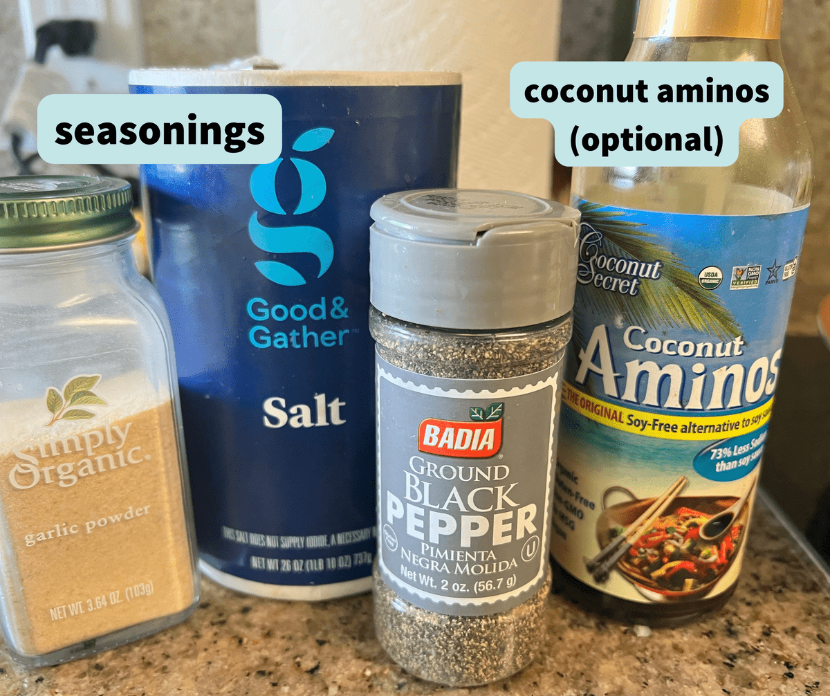 garlic powder, salt, black pepper and coconut aminos in their containers, standing on a kitchen counter