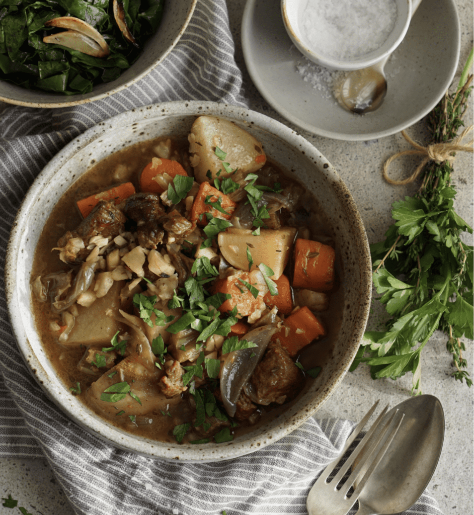 AIP IRish Lamb Stew in a bowl with herbs and spoons, hearty aip recipe