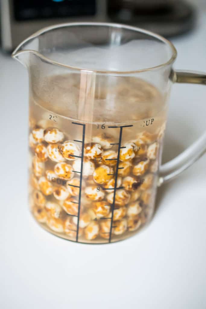 measuring cup with tiger nuts covered with water