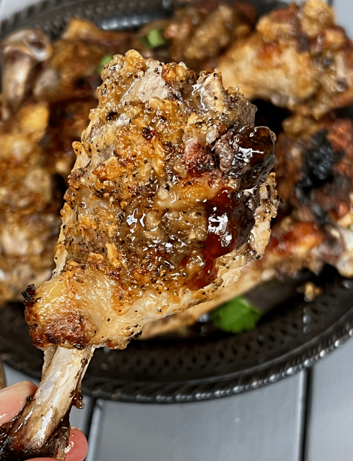 a pile of paleo huli huli chicken drumsticks on a silver platter with cilantro leaves on top