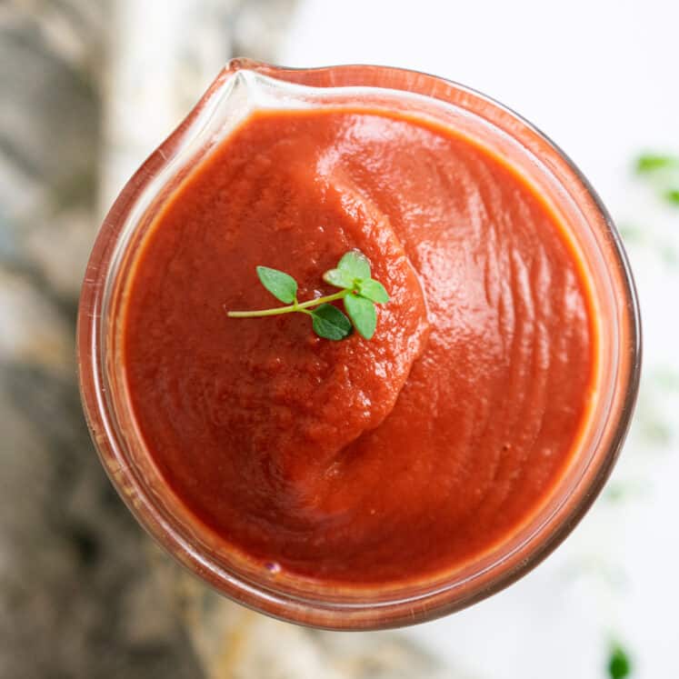 jar with red tomato sauce made with nightshade free vegetables and topped with herbs